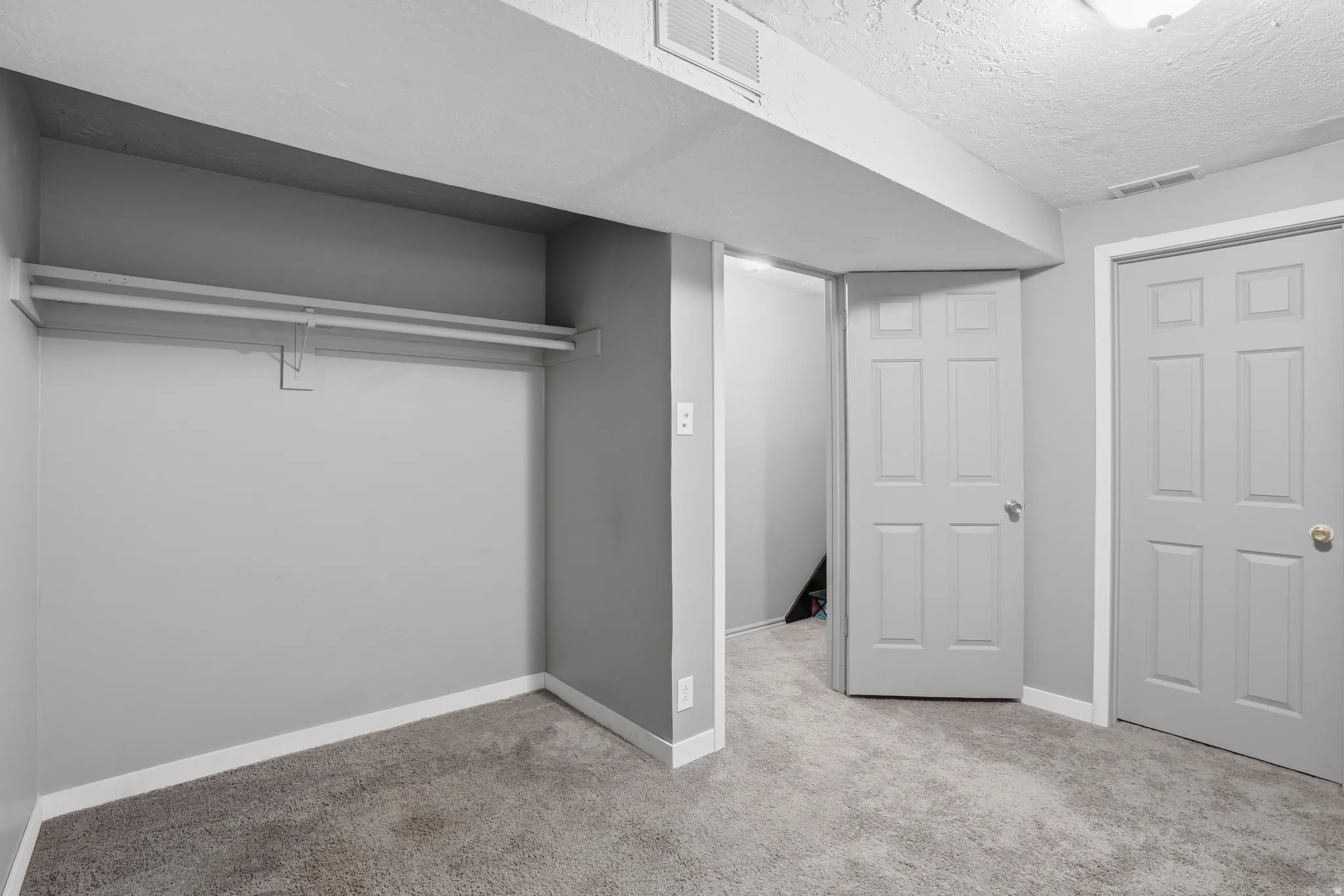 Unfurnished bedroom with light colored carpet and a textured ceiling