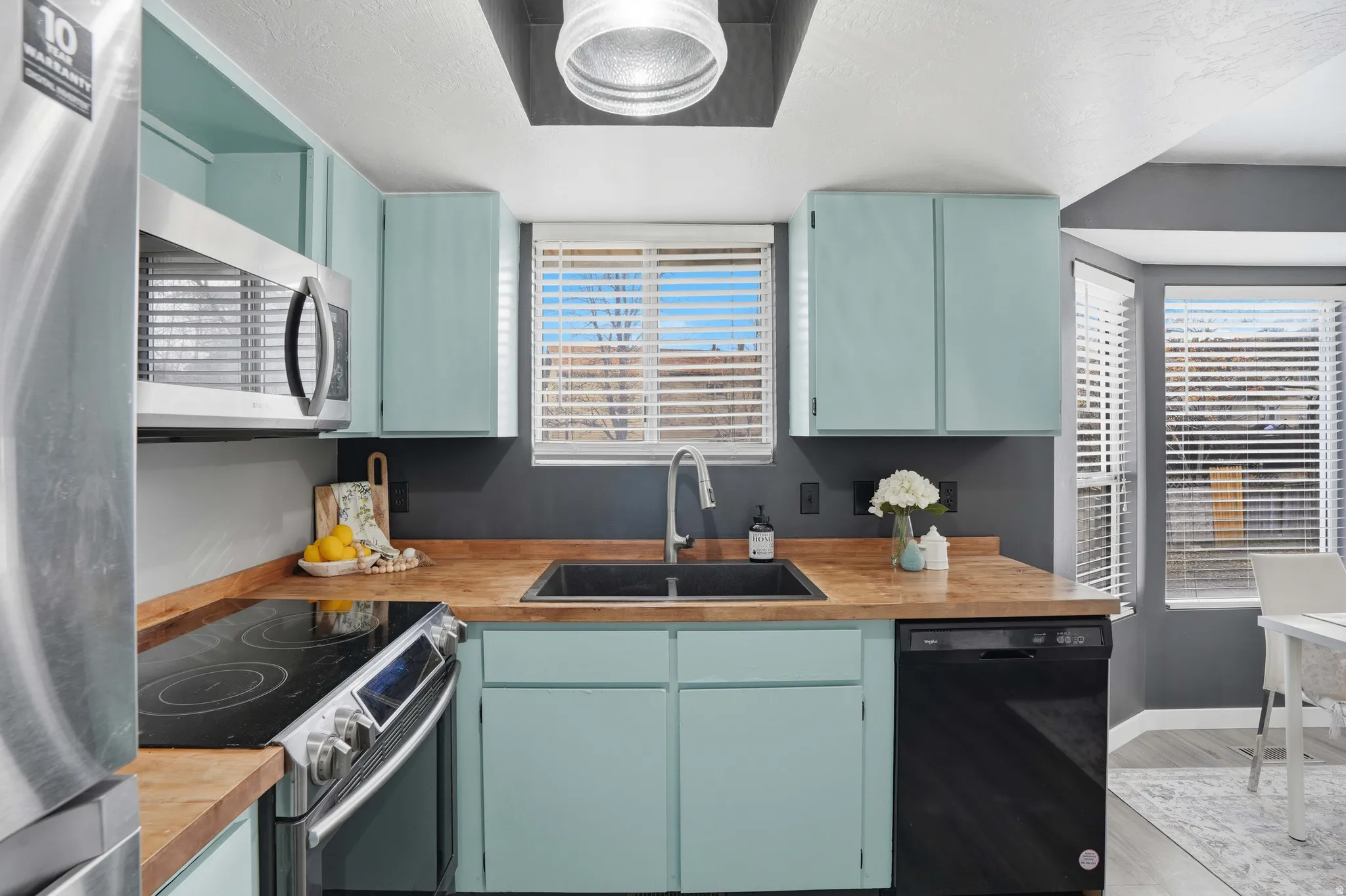 Kitchen featuring stainless steel appliances, light wood finished floors, blue cabinetry, and plenty of natural light