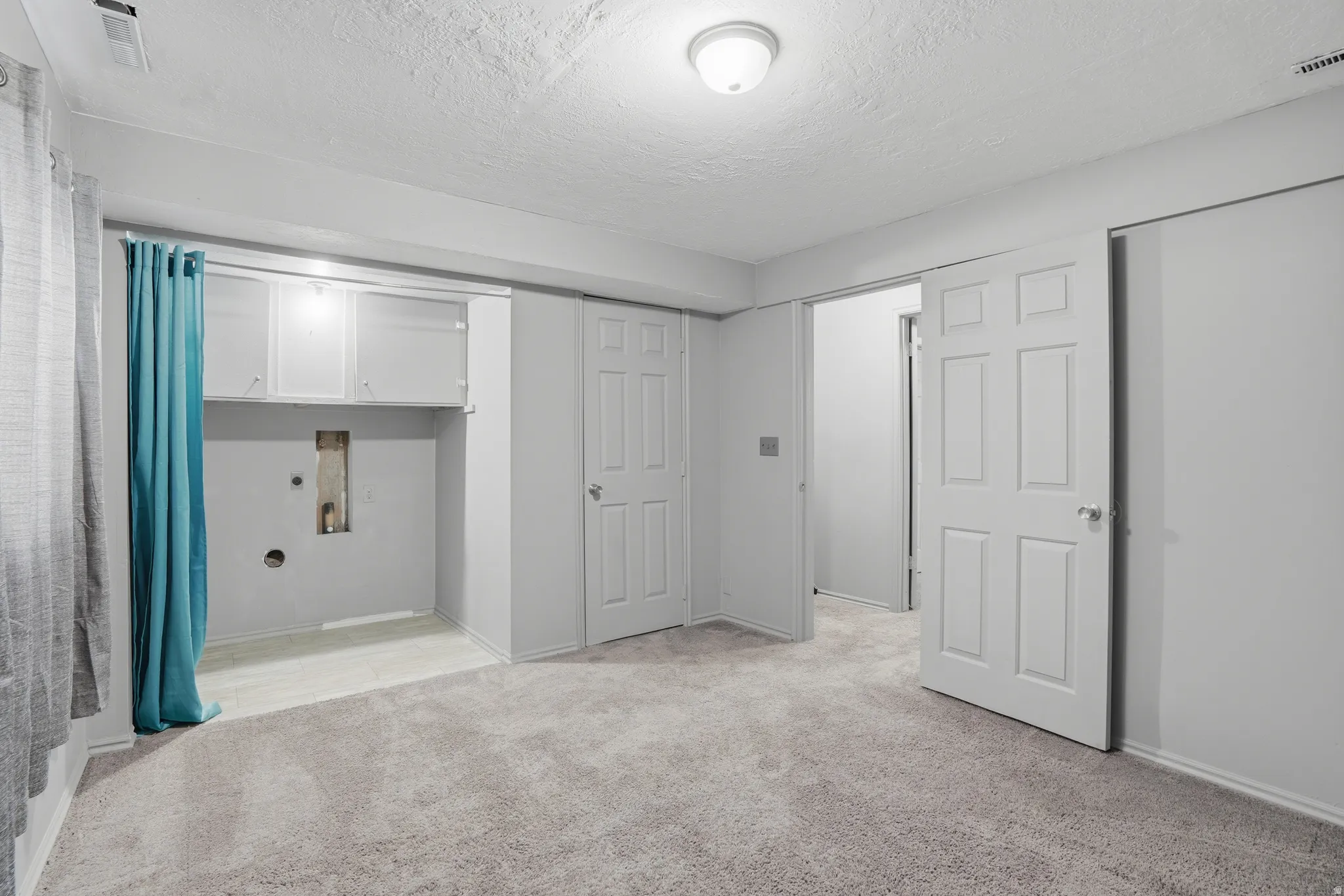Unfurnished bedroom with light colored carpet and a textured ceiling