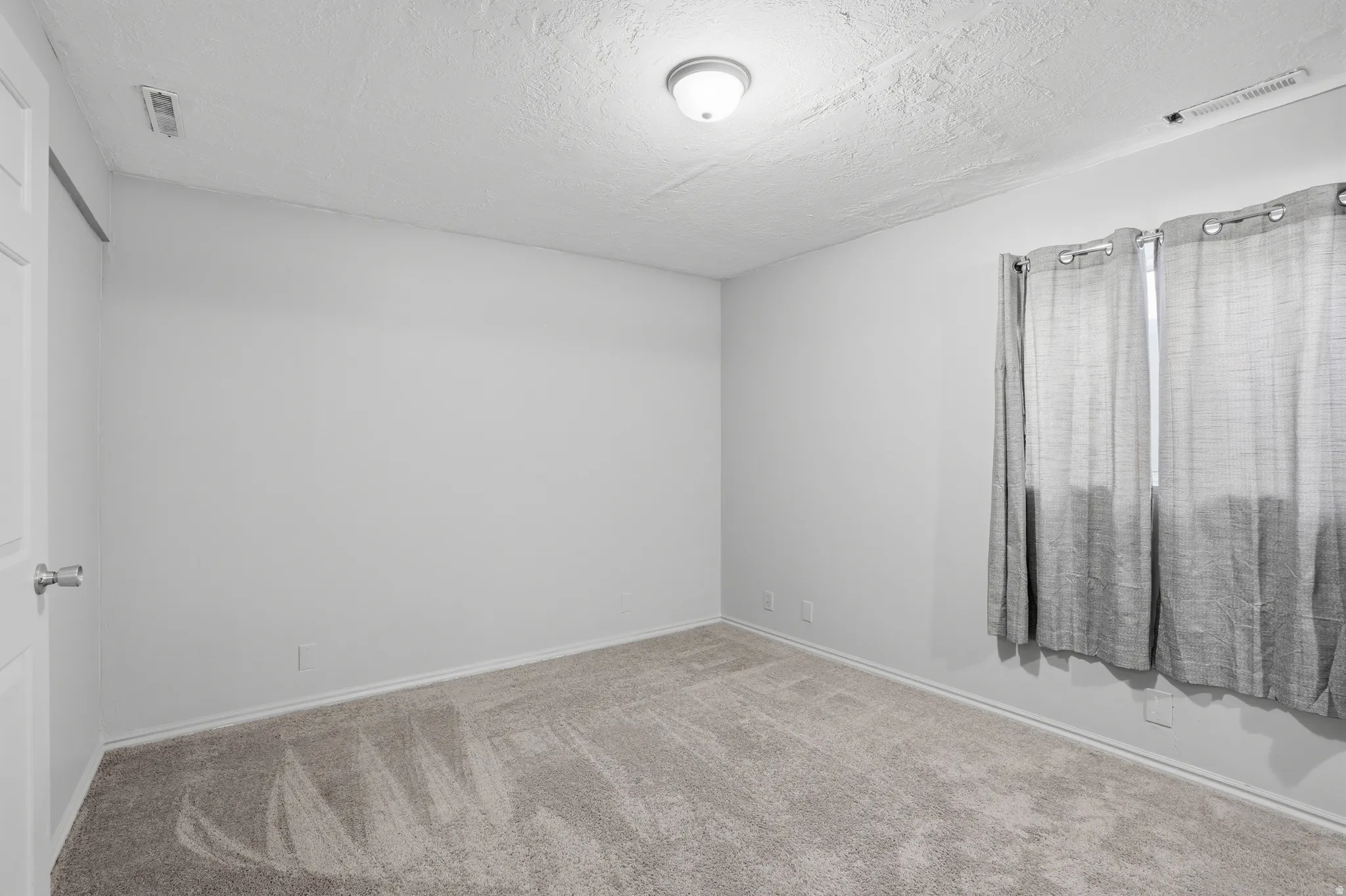 Spare room featuring carpet and a textured ceiling