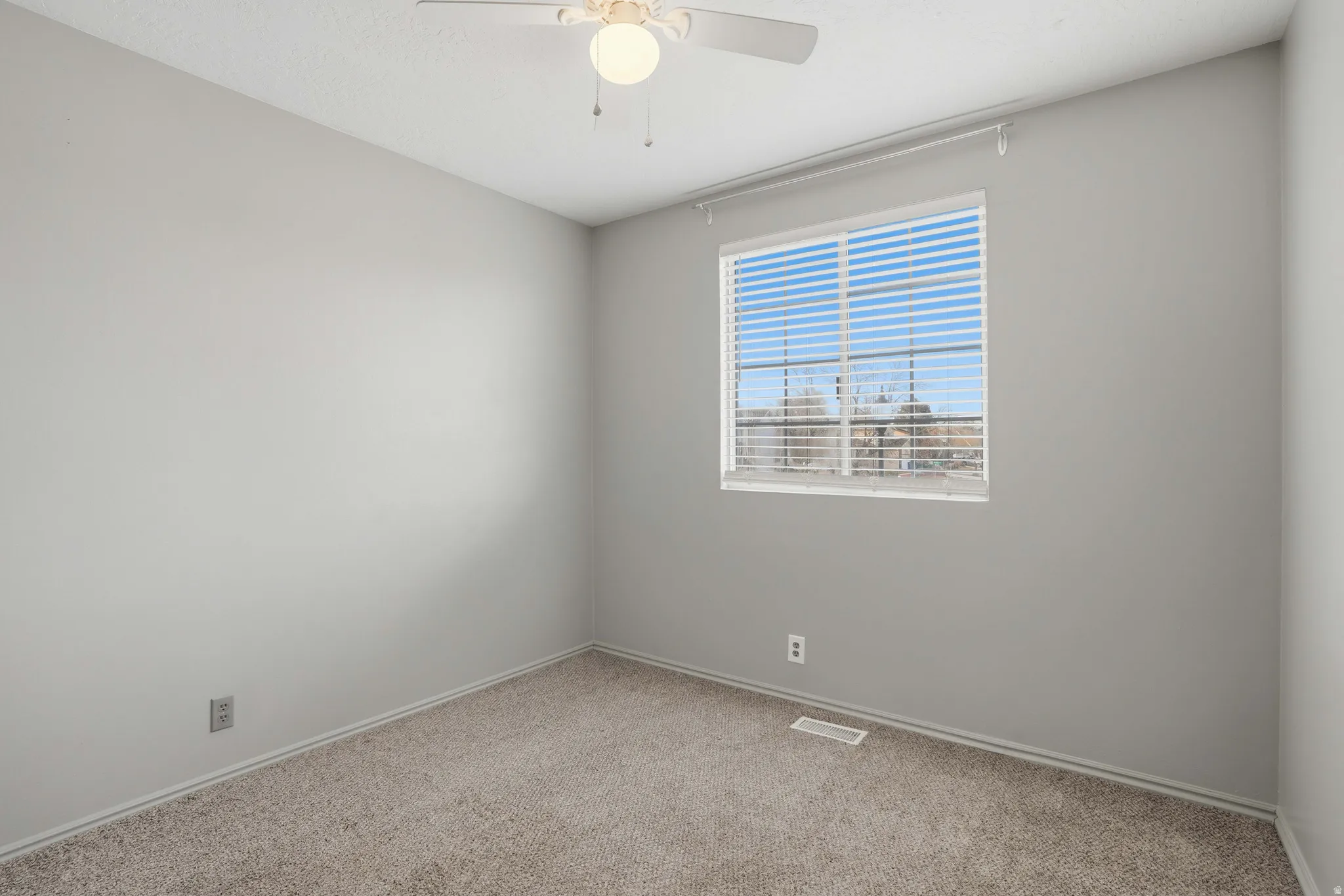 Carpeted empty room with a ceiling fan and baseboards