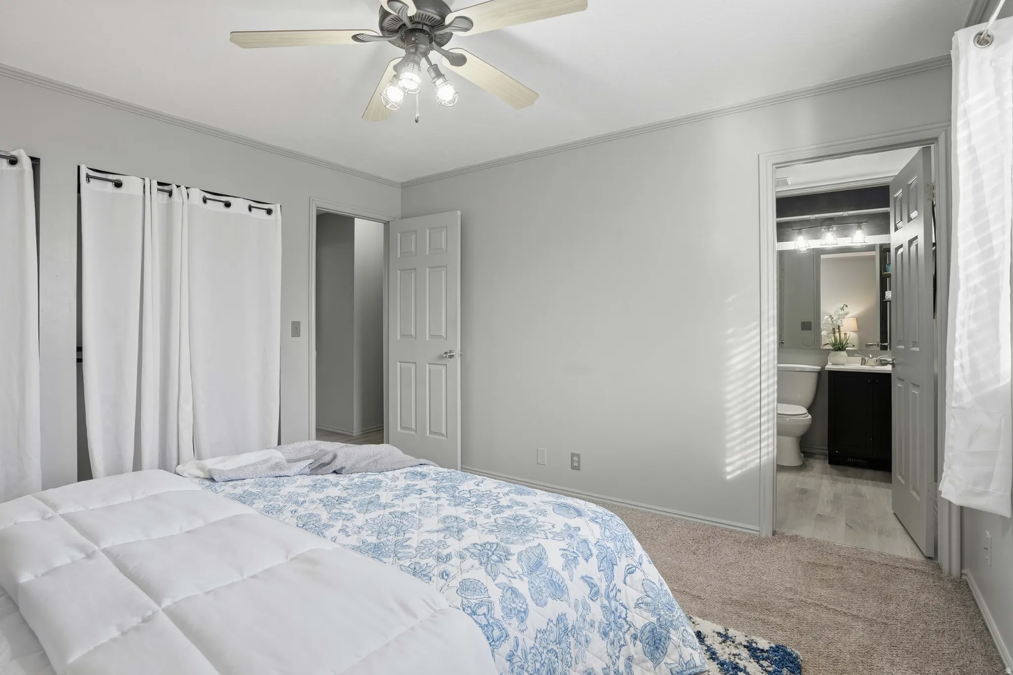 Bedroom featuring light colored carpet, crown molding, a ceiling fan, and connected bathroom