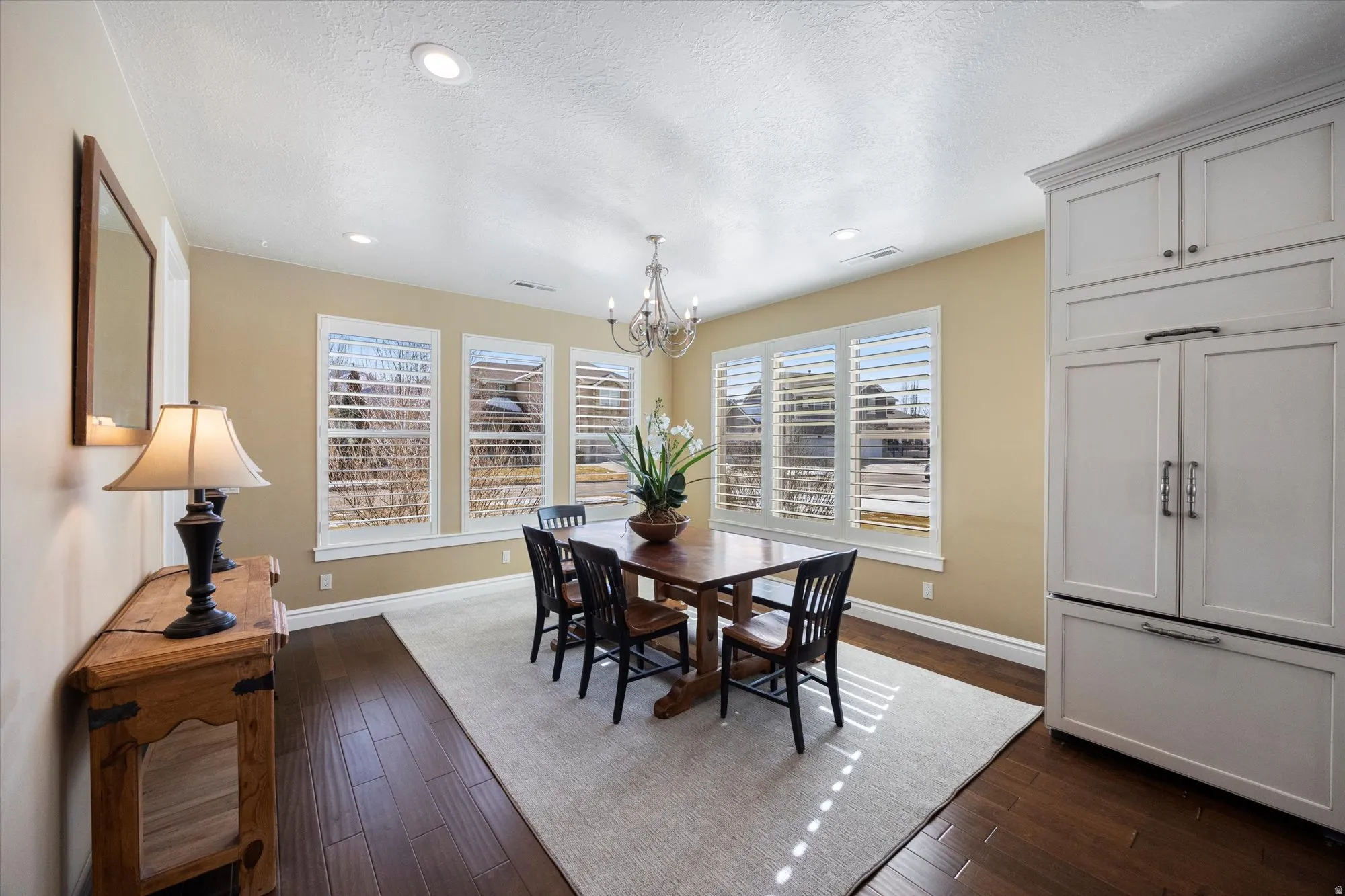 Dining area featuring dark wood-type flooring, hanging lights, and a textured ceiling