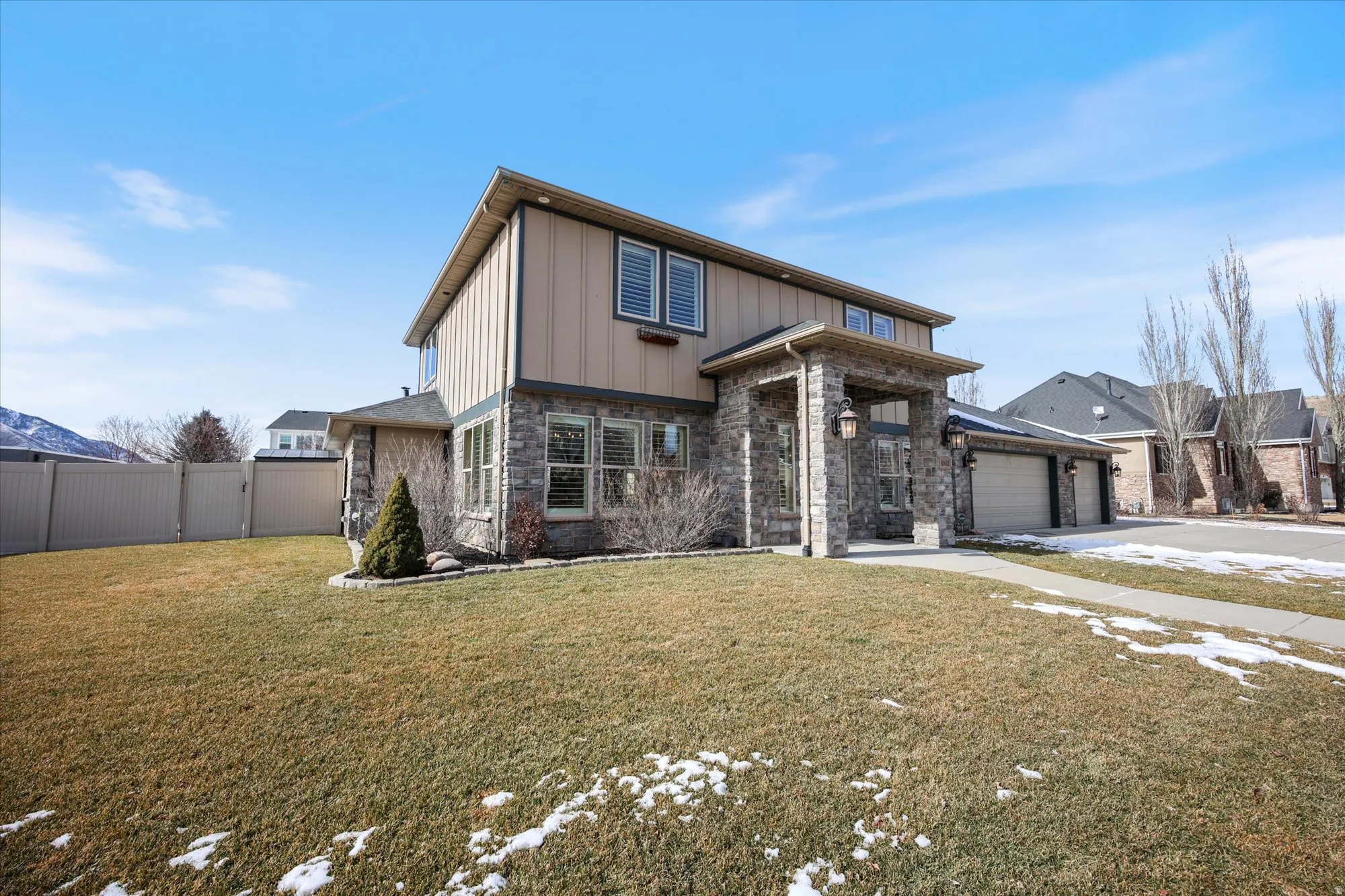 View of front of house with a garage, concrete driveway, stone siding, board and batten siding, and a gate