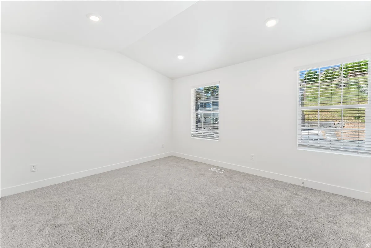 Spare room with lofted ceiling, light carpet, and recessed lighting