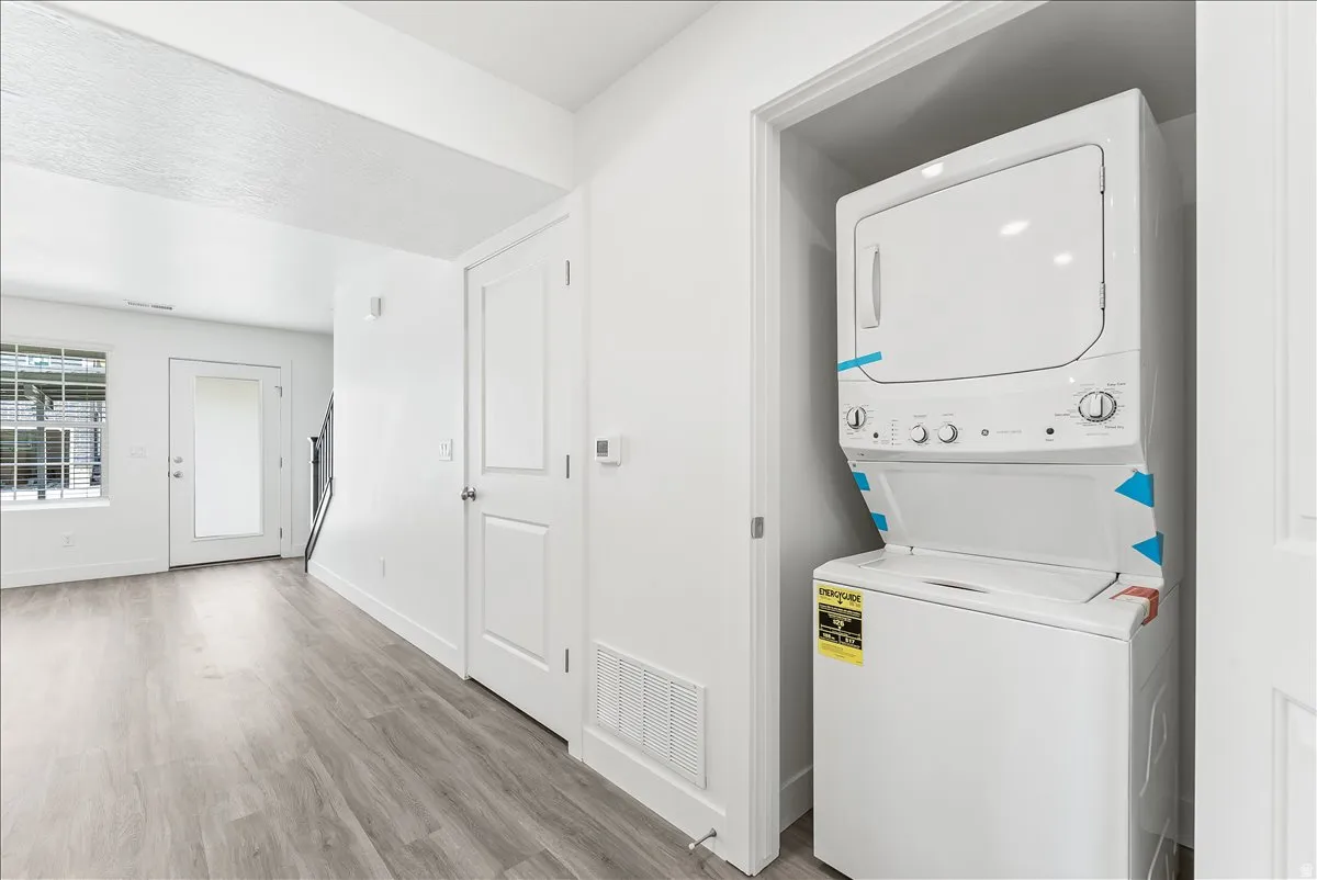 Laundry area featuring stacked washer / drying machine and light wood-style floors