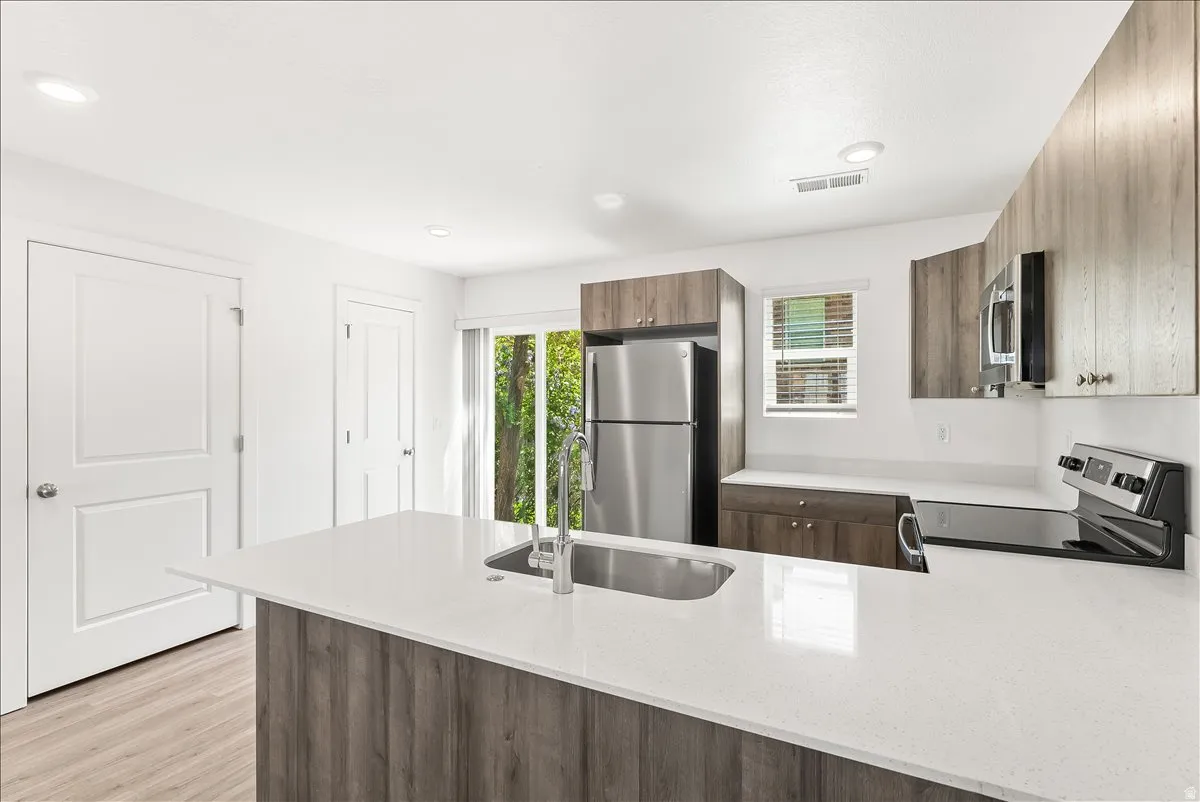 Kitchen featuring stainless steel appliances, light stone countertops, modern cabinets, a peninsula, and healthy amount of natural light