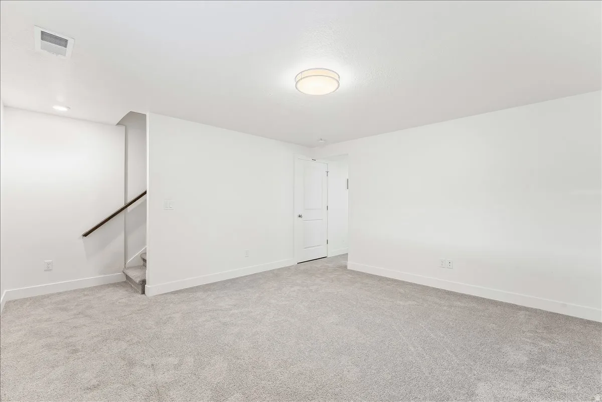 Unfurnished room featuring light colored carpet and stairs