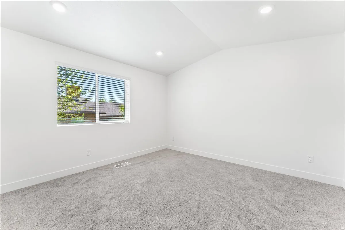 Carpeted spare room featuring lofted ceiling and recessed lighting
