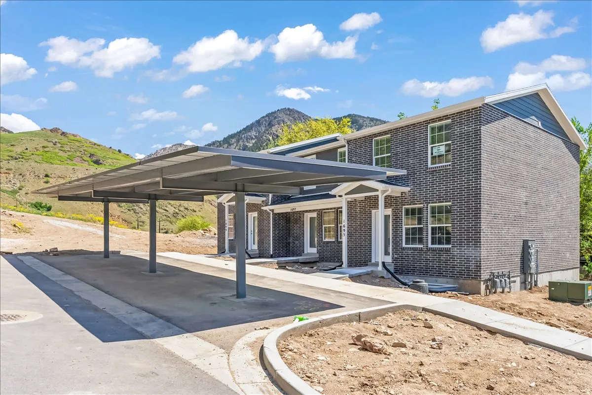 View of front of property featuring brick siding, a mountain view, and covered parking