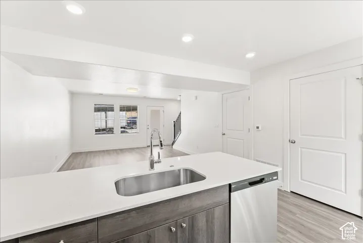 Kitchen with open floor plan, light wood-type flooring, dishwasher, light stone countertops, and recessed lighting