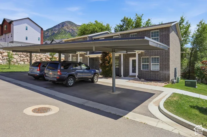 Covered parking structure providing shelter for vehicles, positioned directly outside a brick-faced residential building