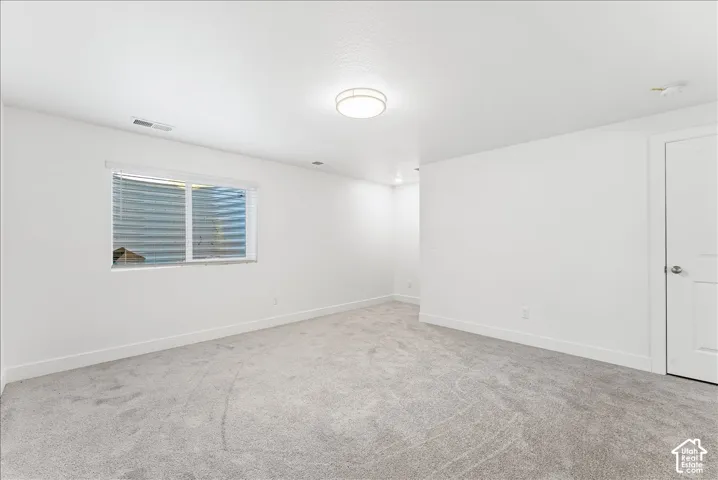 Spare room with baseboards and light carpet