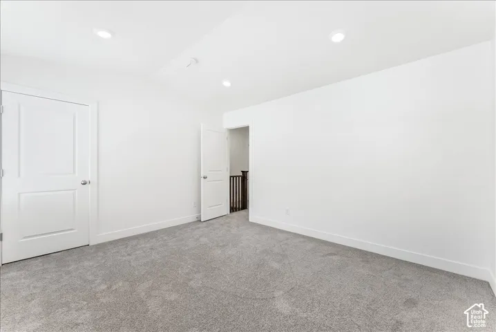 Unfurnished bedroom with light carpet, lofted ceiling, and recessed lighting