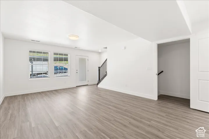 Unfurnished living room with baseboards and light wood-style flooring