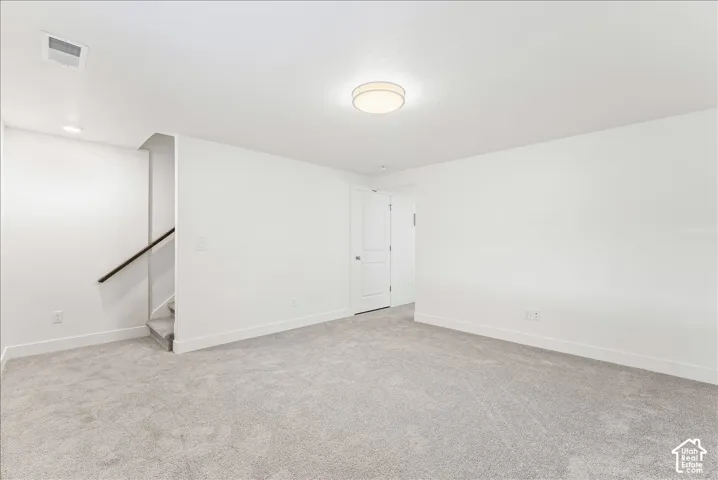 Unfurnished room featuring light colored carpet and stairs