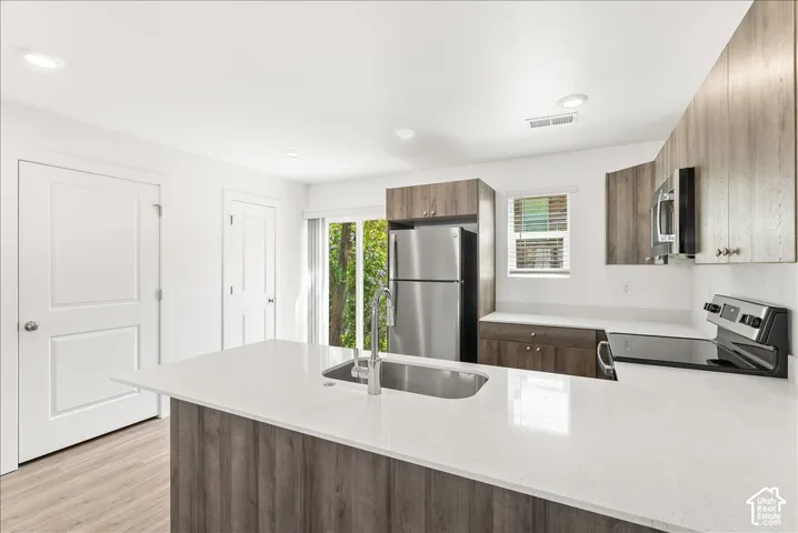 Kitchen featuring stainless steel appliances, light stone countertops, modern cabinets, a peninsula, and healthy amount of natural light