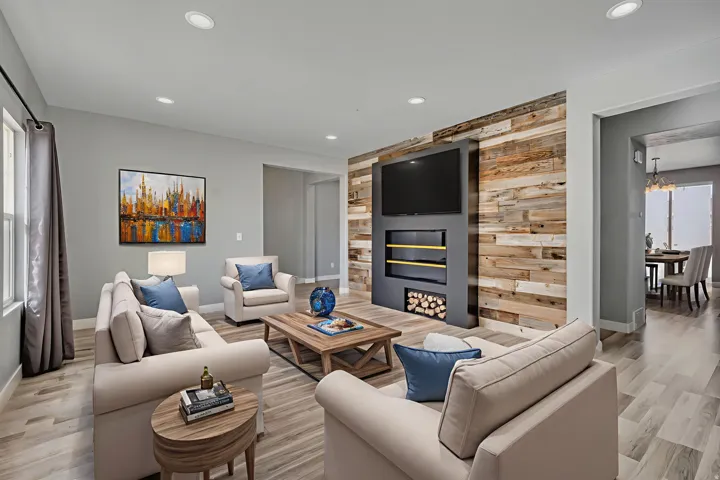 Living area with healthy amount of natural light, wood walls, an accent wall, light wood-type flooring, and recessed lighting