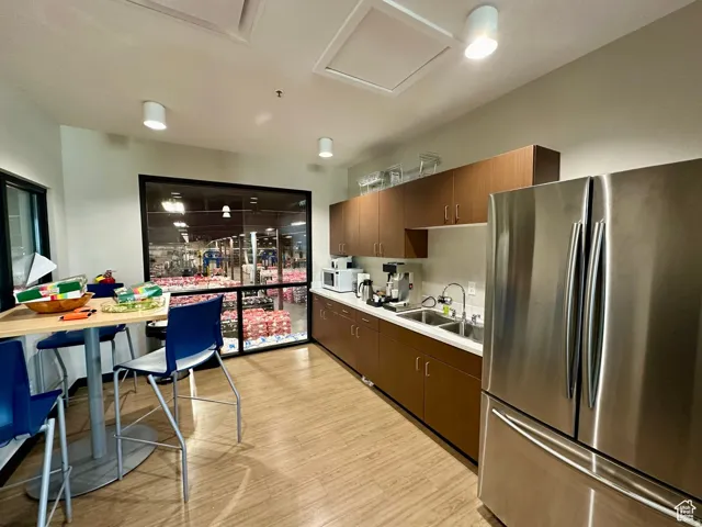 Kitchen featuring freestanding refrigerator, light countertops, light wood finished floors, white microwave, and dark wood finish cabinetry