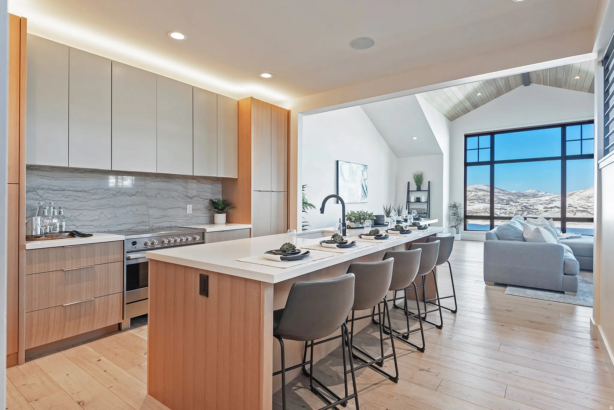 Kitchen featuring two tone cabinets, electric stove, a breakfast bar area, modern cabinets, and light wood-style flooring
