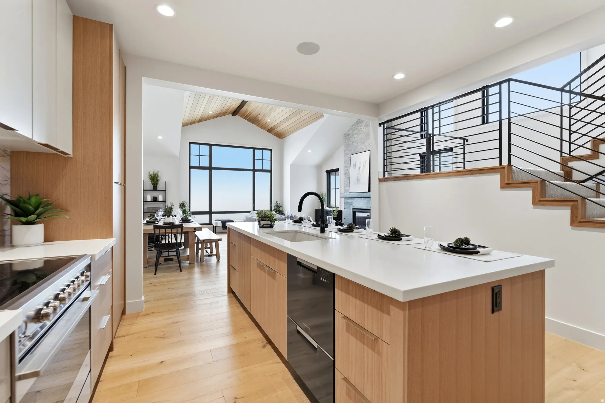 Kitchen featuring modern cabinets, light wood-style floors, an island with sink, stainless steel electric range, and beamed ceiling