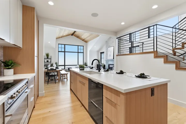 Kitchen featuring modern cabinets, light wood-style floors, an island with sink, stainless steel electric range, and beamed ceiling