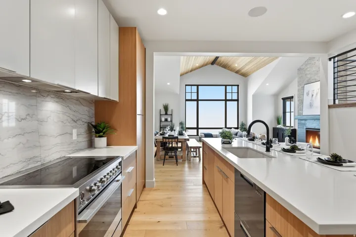 Kitchen featuring stainless steel range, modern cabinets, a lit fireplace, light wood-style flooring, and black dishwasher