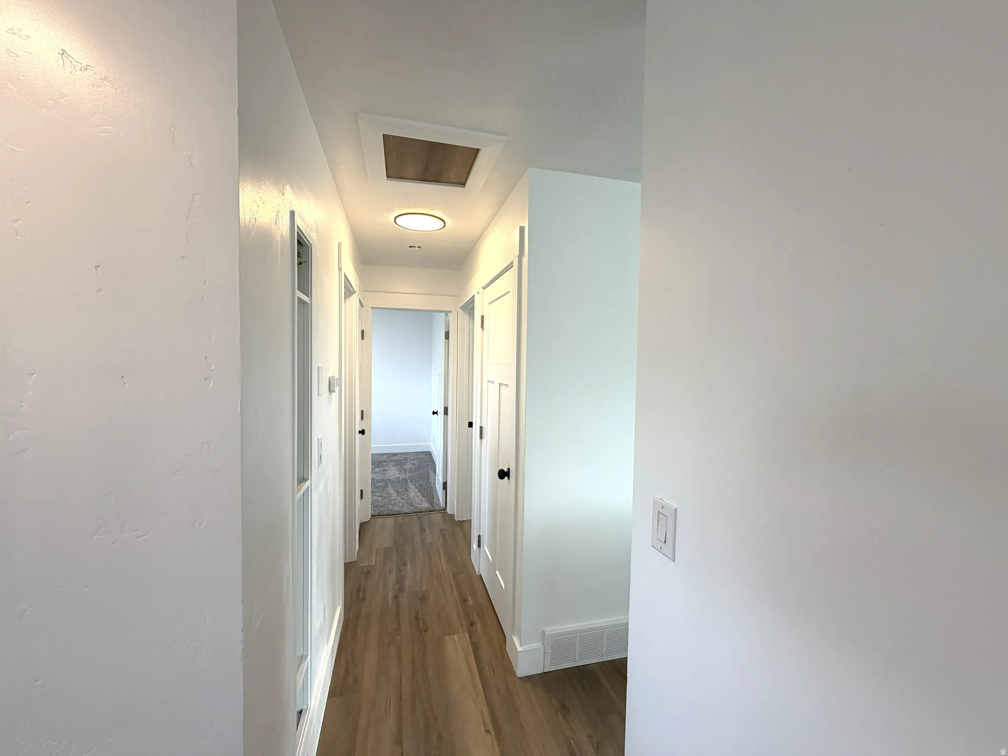 Hallway featuring dark wood finished floors and baseboards