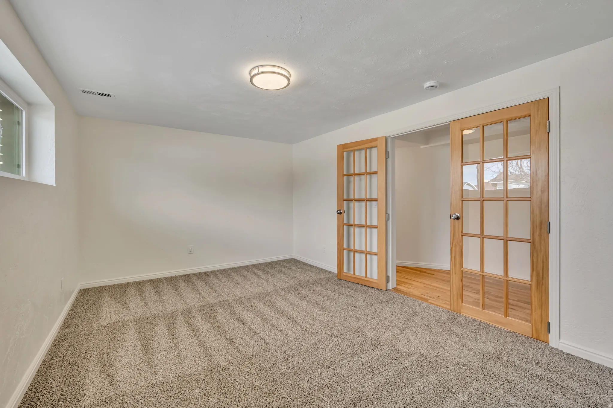 Spare room with light colored carpet, french doors, and healthy amount of natural light