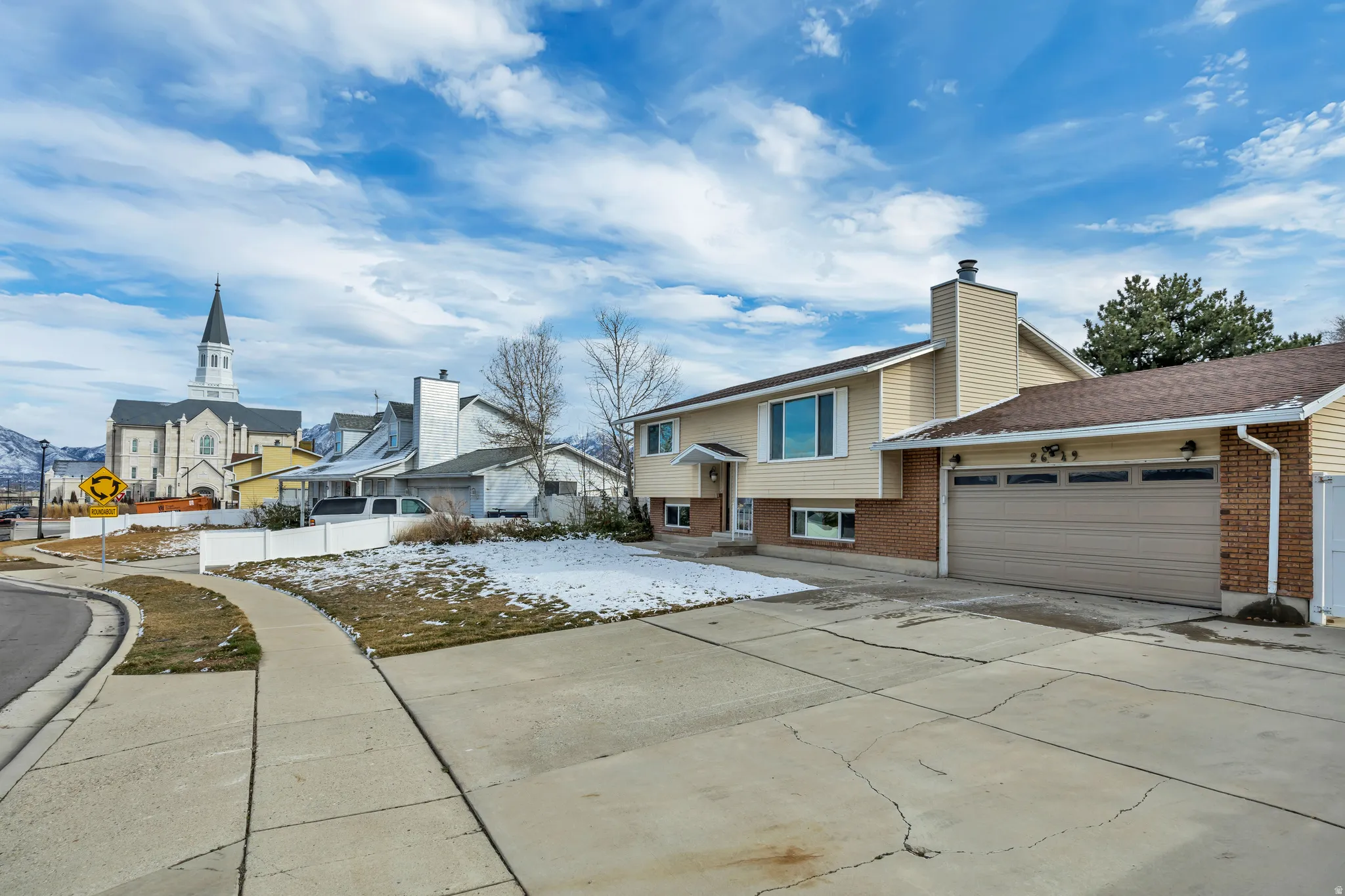 View of front of property featuring brick siding, an attached garage, driveway, and a residential view