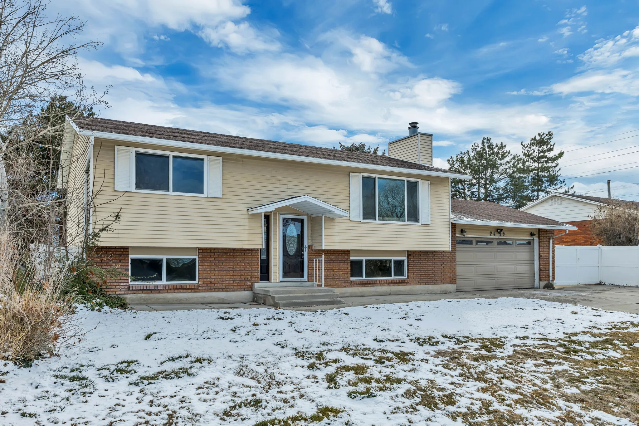 Split foyer home with an attached garage, brick siding, and a chimney