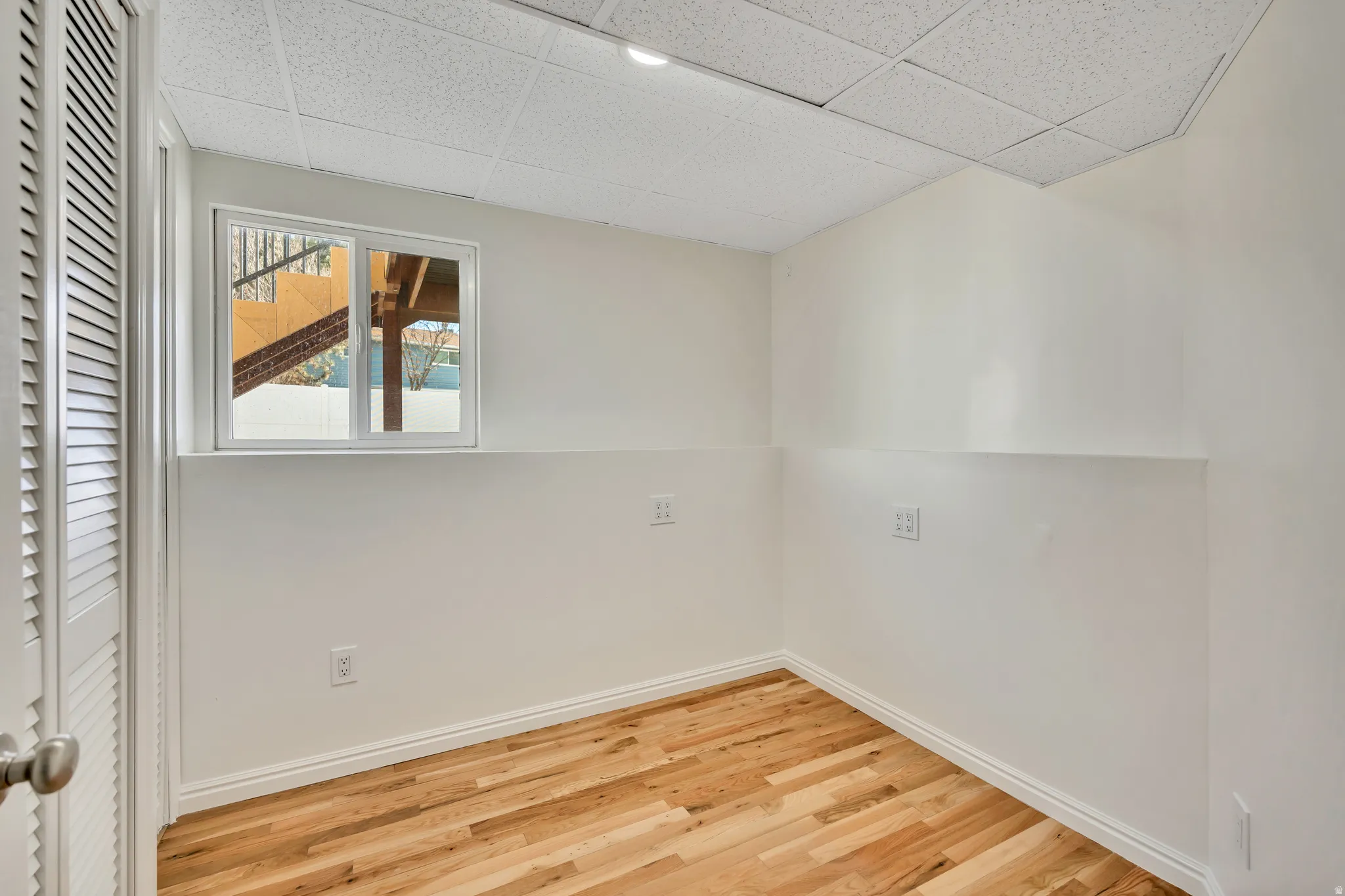 Spare room featuring light wood-type flooring and a paneled ceiling