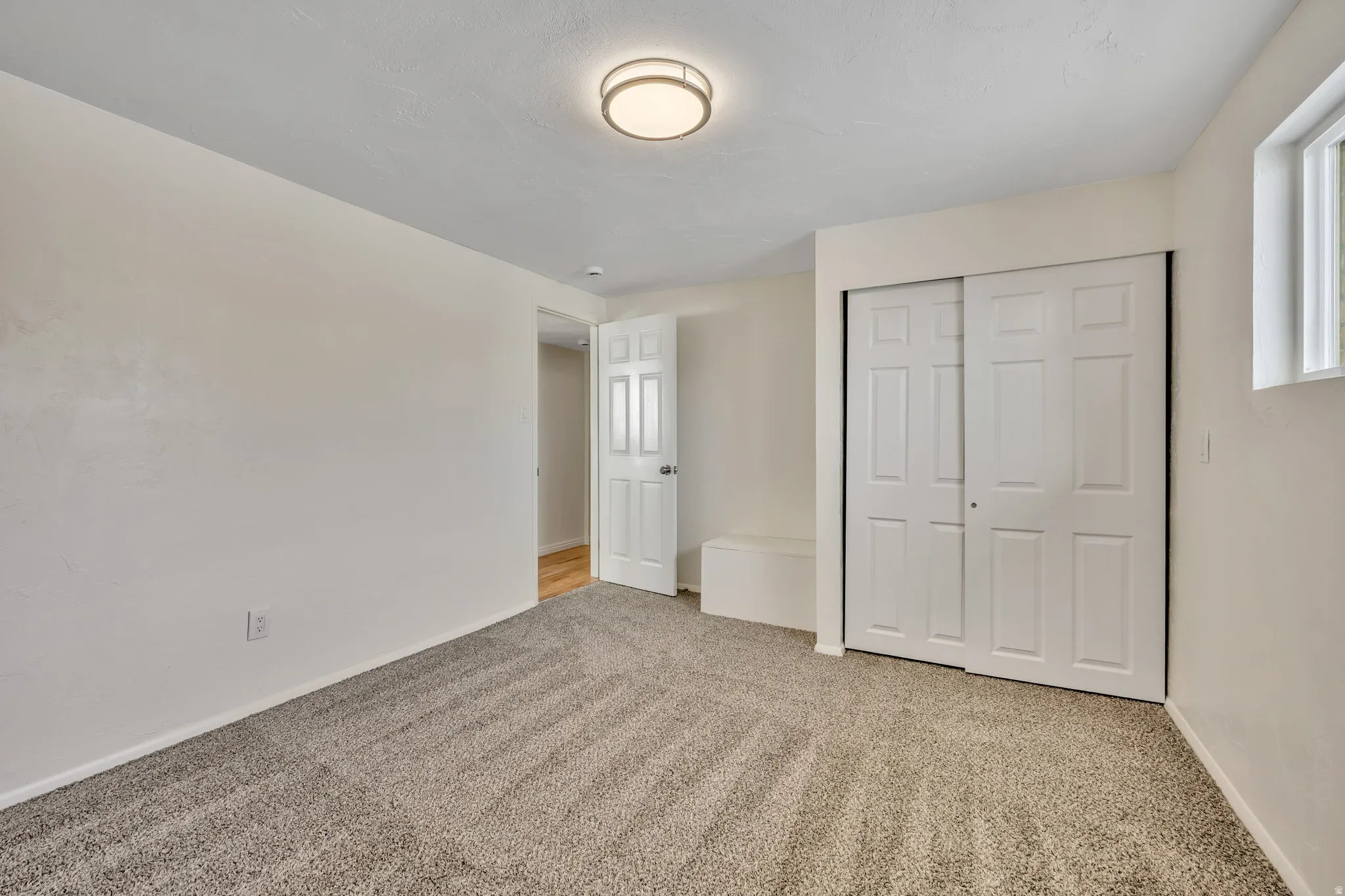 Unfurnished bedroom with light carpet and a closet