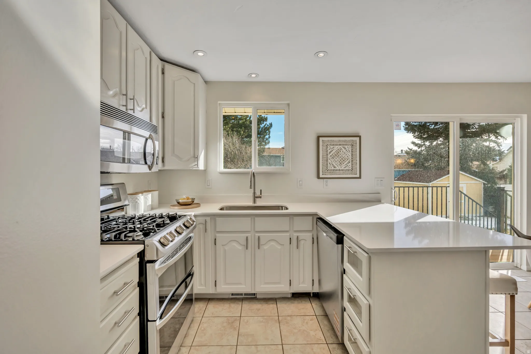 Kitchen featuring stainless steel appliances, a peninsula, white cabinetry, a kitchen breakfast bar, and recessed lighting
