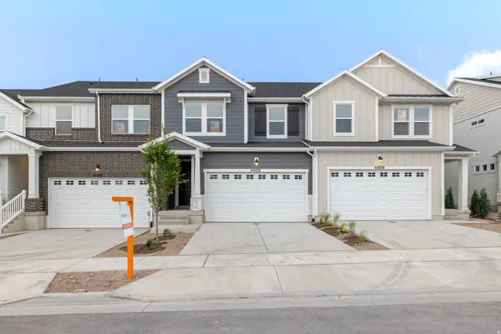 Elegant townhome-style residence featuring a striking two-tone exterior with dark gray and light gray fiber cement siding, complemented by white trim and gabled rooflines