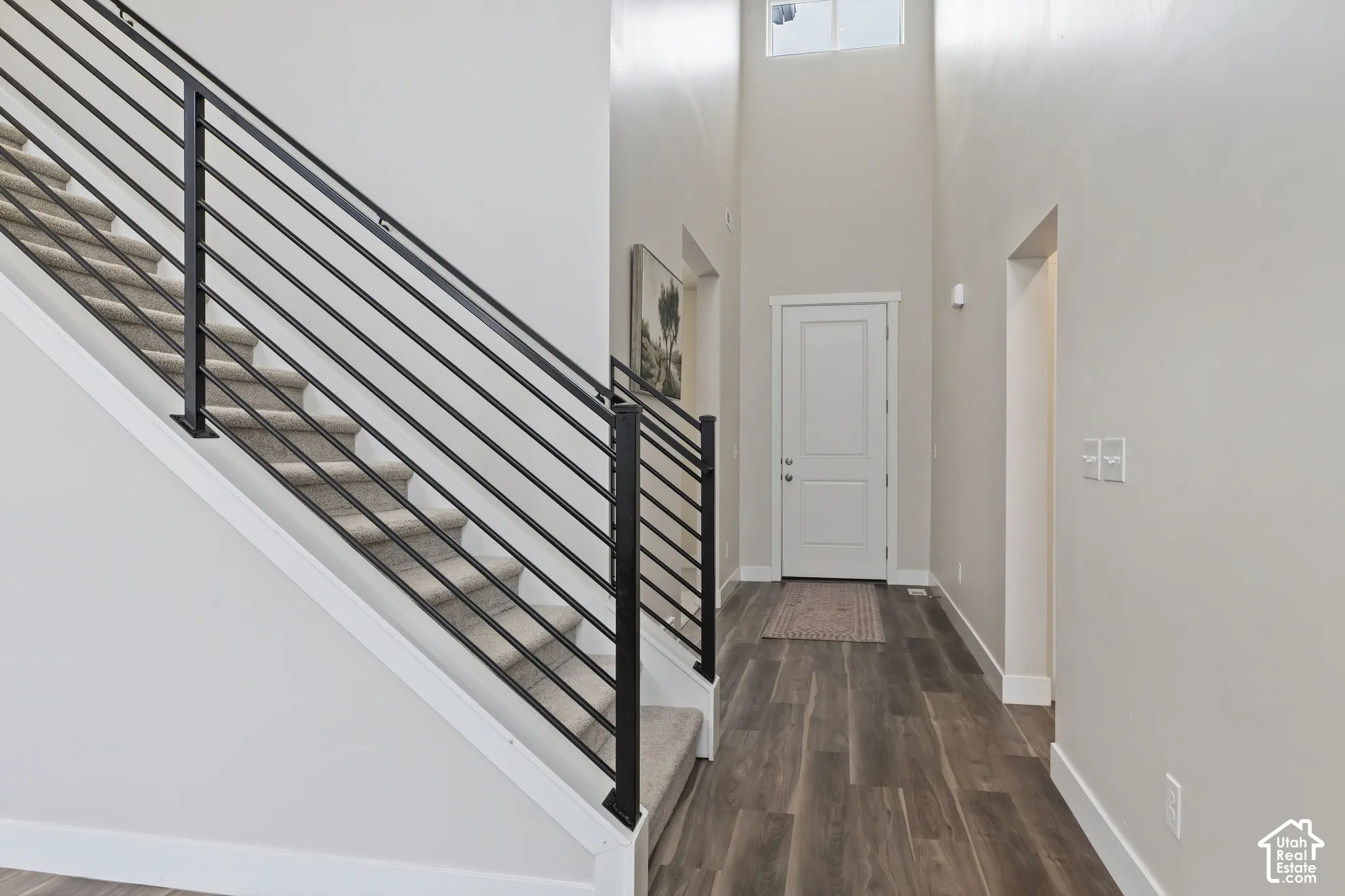 Welcoming entry with soaring ceilings, modern iron staircase railing, and an open view into the main living area.