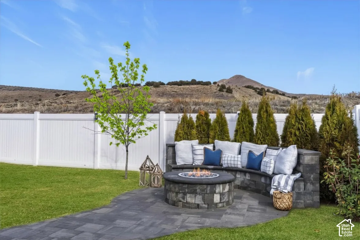 Outdoor living area featuring a built-in gas fire pit, curved seating, and mountain views.