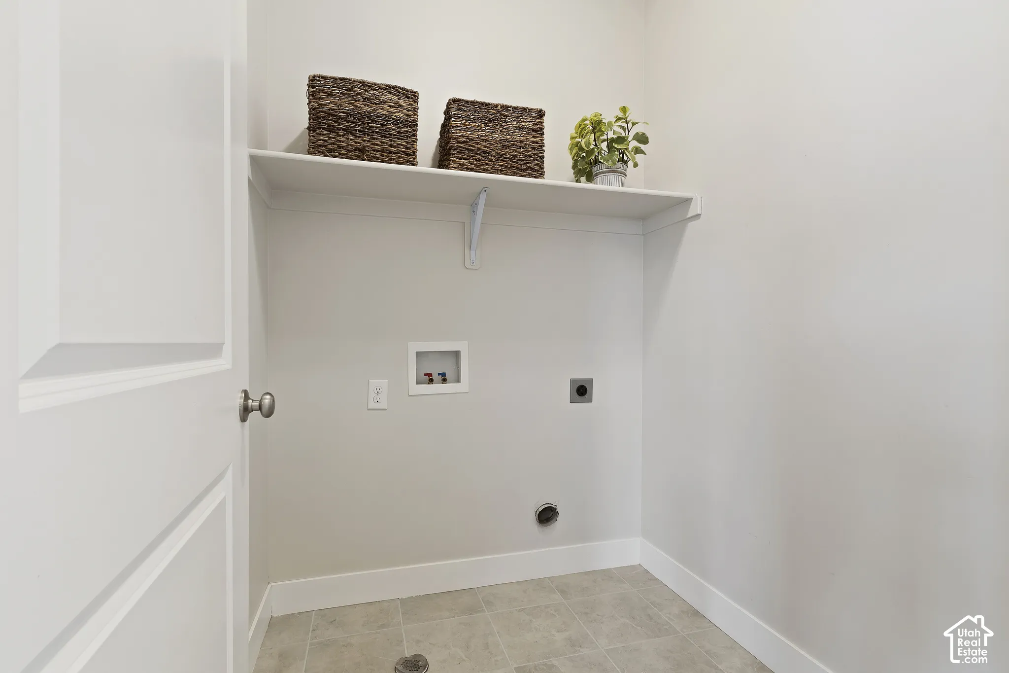 Main-level laundry room with upper shelving, additional storage, and everyday functionality.