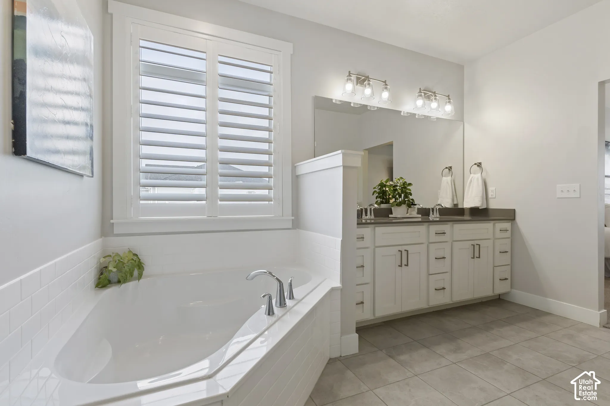 Primary ensuite featuring dual sinks, granite countertops, soaking tub, and abundant cabinet storage.