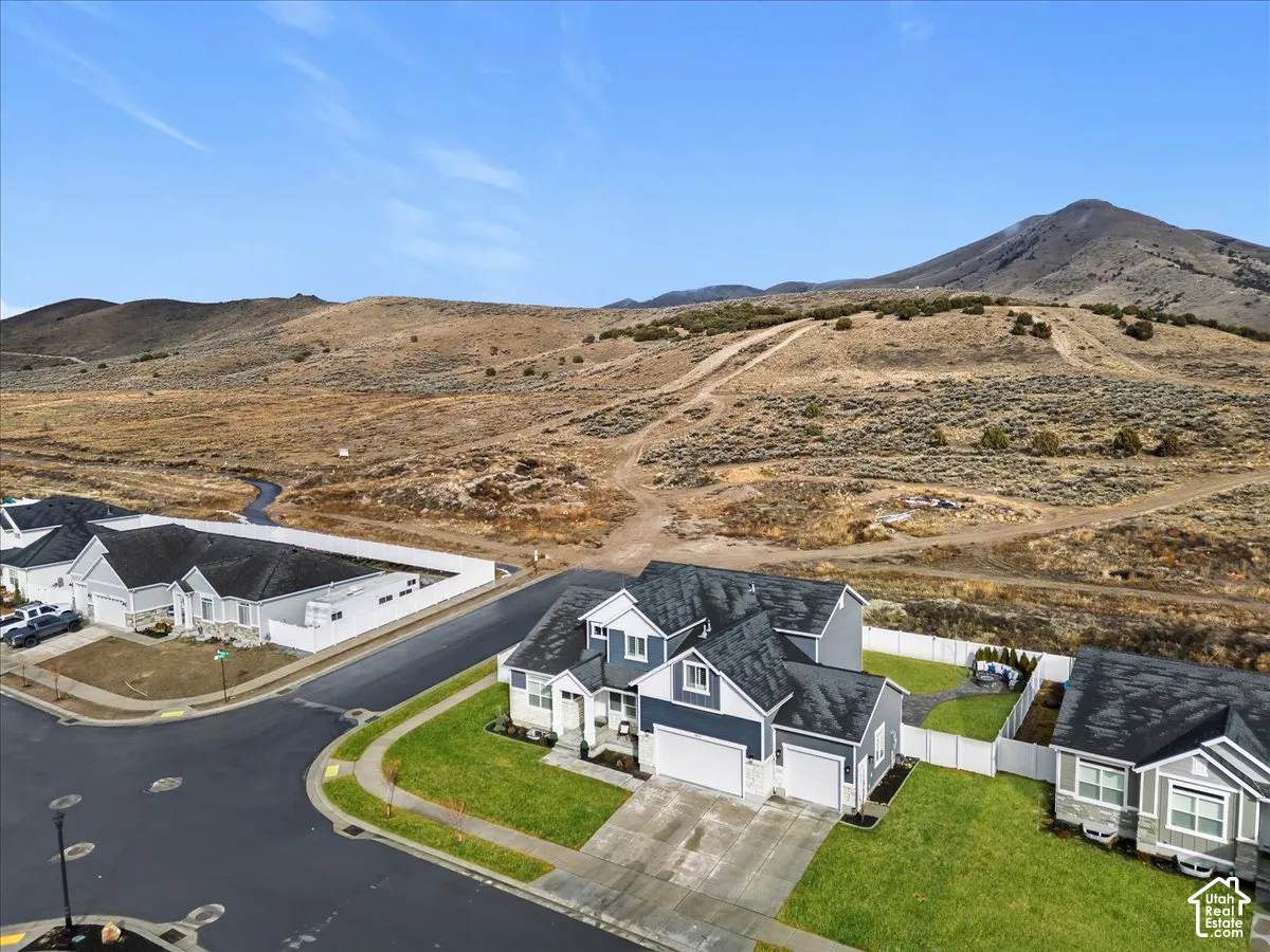 Corner lot with mountain backdrop, mature landscaping, and a fully fenced backyard.