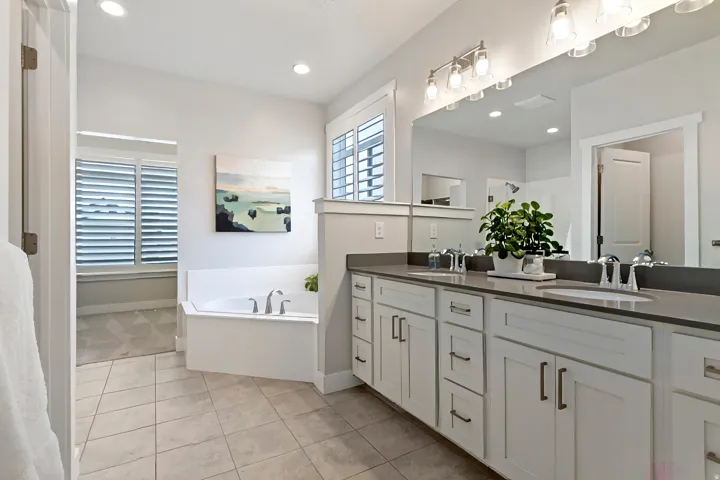 Primary bathroom with dual vanities, soaking tub, separate shower, and spacious layout.