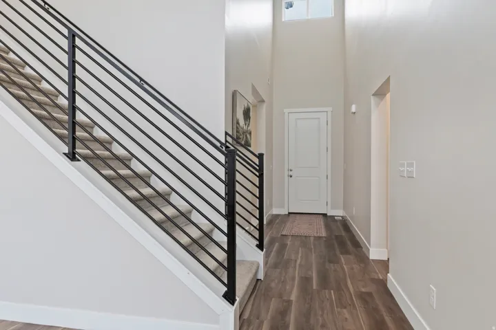 Welcoming entry with soaring ceilings, modern iron staircase railing, and an open view into the main living area.