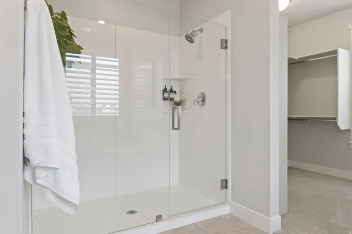 Glass-enclosed shower with adjacent soaking tub and oversized walk-in closet in the primary suite.