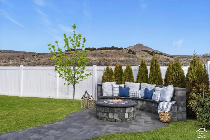 Outdoor living area featuring a built-in gas fire pit, curved seating, and mountain views.
