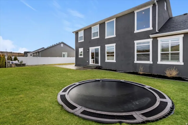 Backyard view highlighting the spacious lawn, privacy fencing, and mountain backdrop.