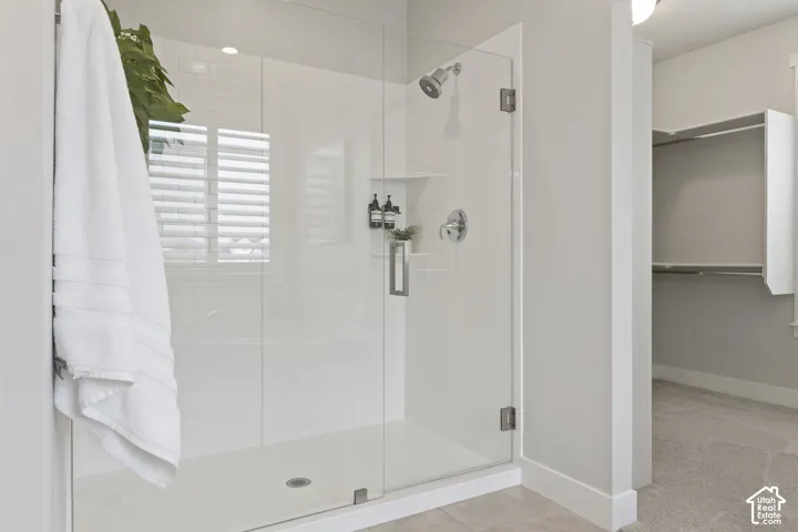 Glass-enclosed shower with adjacent soaking tub and oversized walk-in closet in the primary suite.