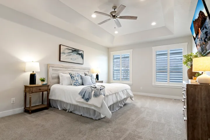 Main-level primary suite featuring a tray ceiling, oversized walk-in closet, and spacious ensuite bathroom.