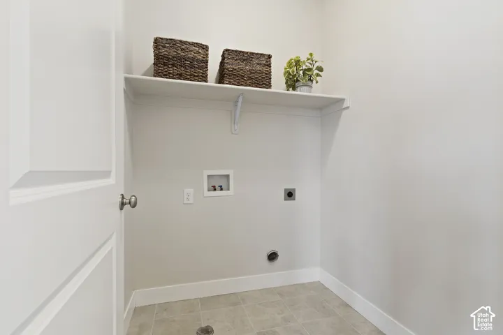 Main-level laundry room with upper shelving, additional storage, and everyday functionality.