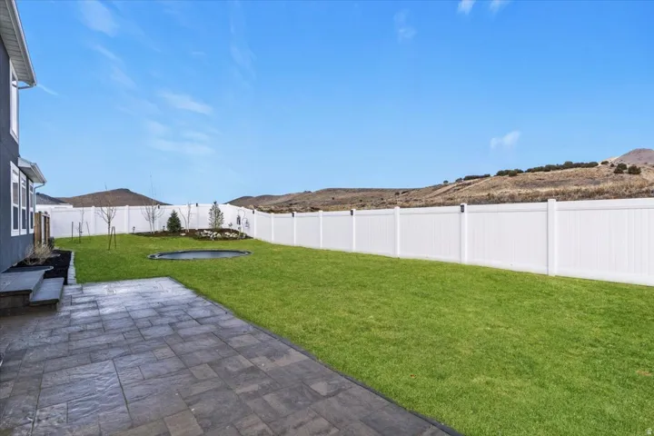 Flat, fully fenced backyard with extended paver patio and room for pets, play, or future landscaping.