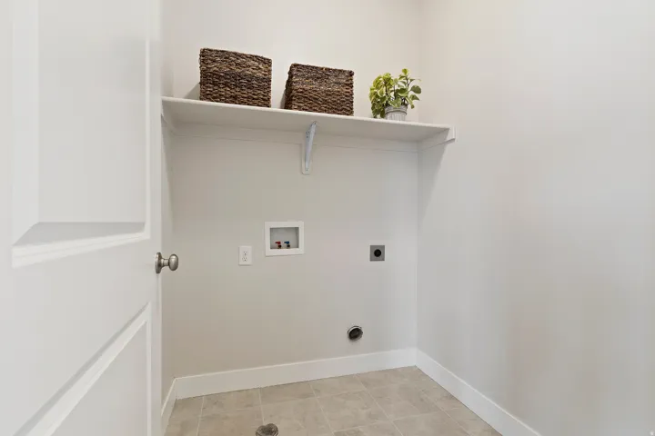 Main-level laundry room with upper shelving, additional storage, and everyday functionality.